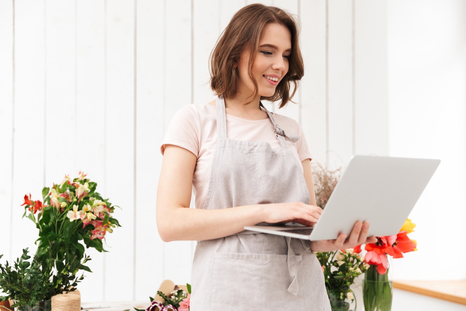 Florist smiling while using a laptop in her flower shop