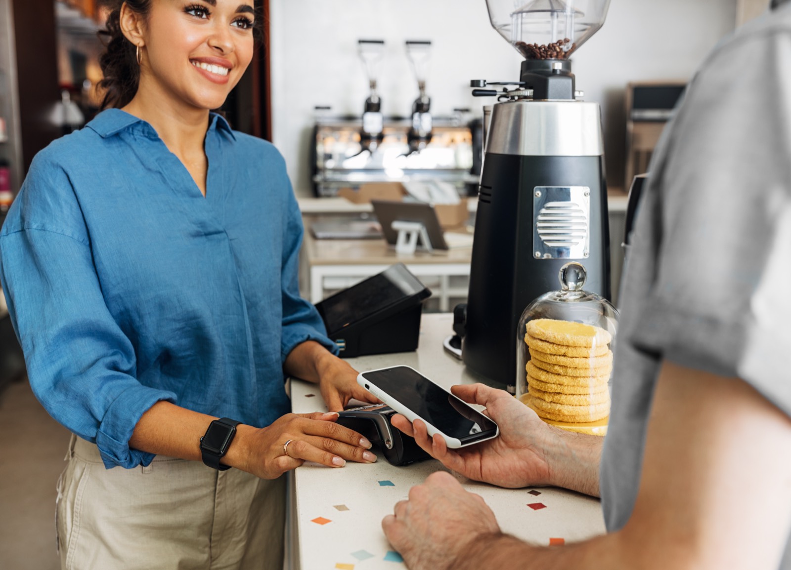 Smiling cafe owner taking a phone payment at the counter