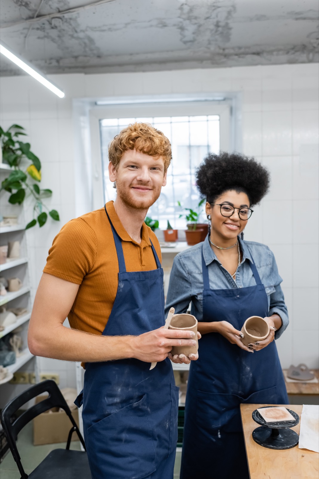 Two studio owners holding mugs in their workshop